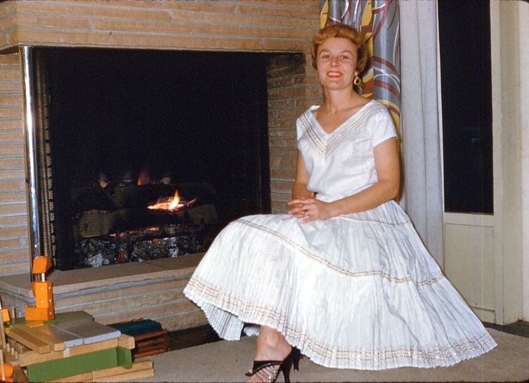 Frances Peterson, mother of Joel Peterson, sitting by a fireplace.